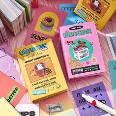 several different types of candy and books on a pink table with some writing utensils