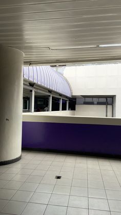 an empty room with tiled flooring and purple wall in the center, next to a white building