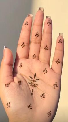 a person's hand with some small tattoos on their fingers and thumbnails