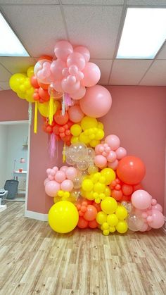 a room with balloons and streamers hanging from the ceiling in front of a pink wall