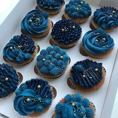 twelve blue decorated cupcakes in a white box