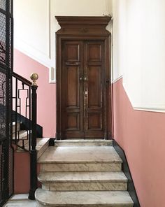 a wooden door sitting on the side of a set of stairs next to a pink wall