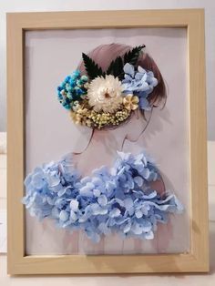 a woman with flowers in her hair is framed in a wooden frame on the table