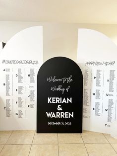 a black and white wedding sign with names on it in front of a wall that says welcome to the wedding of kelian & warnen