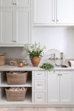 a kitchen with white cabinets and baskets on the counter top, along with other items