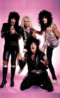 the band kiss posing in front of a pink background