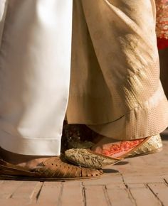 two people standing next to each other on a brick floor with their feet in the air