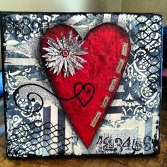 a red heart with snowflakes on it sitting on top of a wooden table