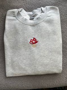 a gray sweatshirt with a red mushroom embroidered on it