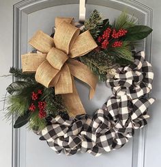 a christmas wreath hanging on the front door with evergreen, berries and burlock