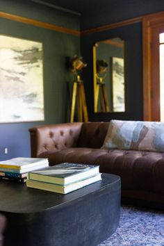 two books are sitting on top of a coffee table in front of a couch and mirror