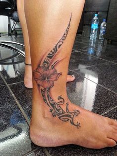 a woman's foot with a flower tattoo on the side of her leg and an arrow in the middle