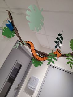 an office decorated with paper cutouts and jungle animals hanging from the ceiling in front of a door