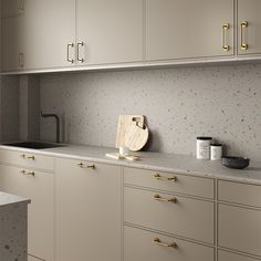 a kitchen with white cabinets and gold handles on the countertops, along with a cutting board