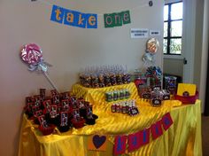 a table topped with lots of candy next to a sign that says, take one