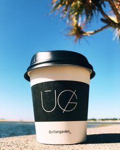 a coffee cup sitting on top of a sandy beach