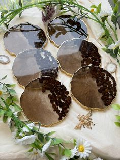 four decorative plates sitting on top of a table covered in flowers and leaves, next to an insect