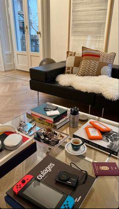 a living room filled with lots of furniture and books on top of a glass coffee table