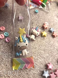 someone is holding a tiny toy unicorn in a clear box with other toys around it