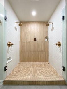 an empty bathroom with wooden flooring and white tiles on the walls, along with two urinals