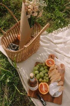 a picnic is set out on the grass with wine, cheese and fruit in baskets