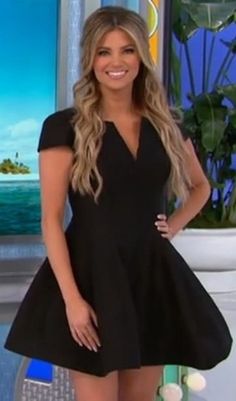 a woman in a short black dress posing for a photo on the set of news