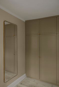 an empty room with wooden floors and beige cabinets in front of a large mirror on the wall