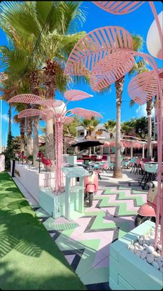 an outdoor area with palm trees and lawn furniture on the grass, surrounded by pink umbrellas