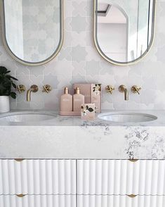 a bathroom with two sinks and mirrors on the wall next to it is a plant