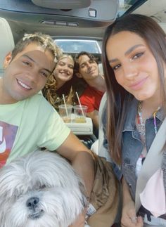 a group of people sitting in the back of a car with a dog on their lap