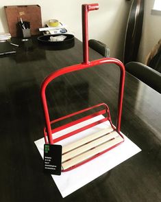 a red chair sitting on top of a wooden table next to a desk with a sign