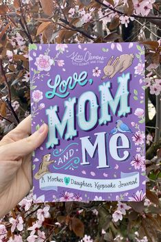 someone holding up a card with the words love mom and me in front of some flowers