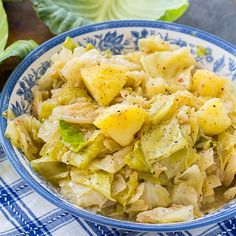 a bowl filled with cabbage and potatoes on top of a blue and white checkered table cloth