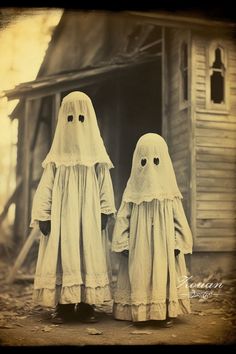 two children dressed as ghost standing in front of an old house with their heads turned to look like they are holding hands