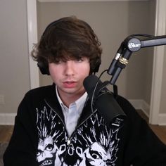 a boy with headphones on sitting in front of a microphone and looking at the camera