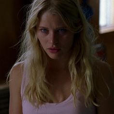 a blonde woman in a pink tank top looking at the camera