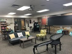 a room with couches, tables and chairs in front of a projector screen