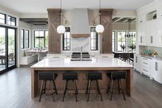 a large kitchen with an island in the middle and three bar stools at the end