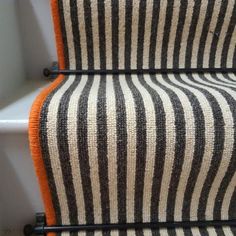 an orange and black striped blanket sitting on top of a white toilet