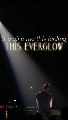 a man standing in front of a microphone under a spotlight with the words, you give me this feeling this everglow