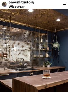 a kitchen with blue walls and wooden counter tops next to a bar area that has shelves on the wall