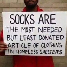 a man holding a sign that says socks are the most needed but least dona article of clothing in homeless shelters