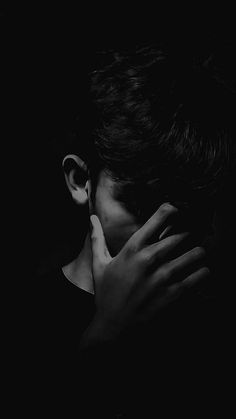 black and white photograph of a woman holding her hands to her face in the dark