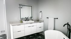 a white bath tub sitting next to a bathroom sink under a large mirror above it