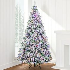 a white christmas tree with purple and green decorations