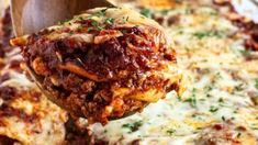 a wooden spoon is lifting up some lasagna casserole