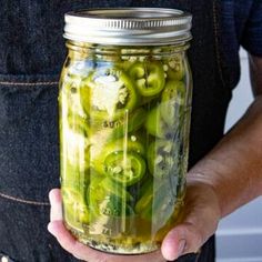 a person holding a mason jar filled with pickles