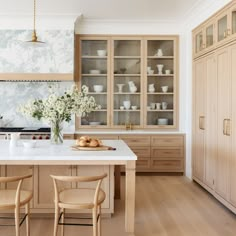 a kitchen with wooden cabinets and white counter tops, along with two bar stools