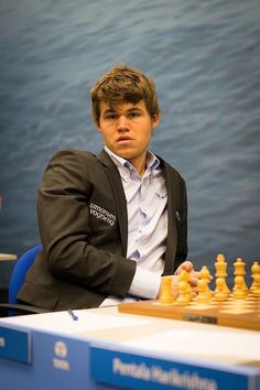 a man sitting at a table with a chess board and pieces in front of him