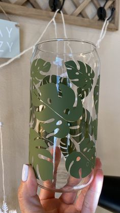 a person holding up a glass with leaves on it